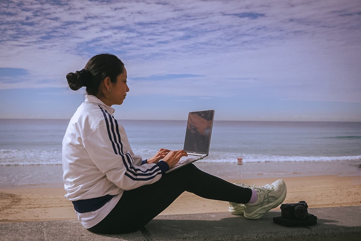 Woman working on laptop at the beach