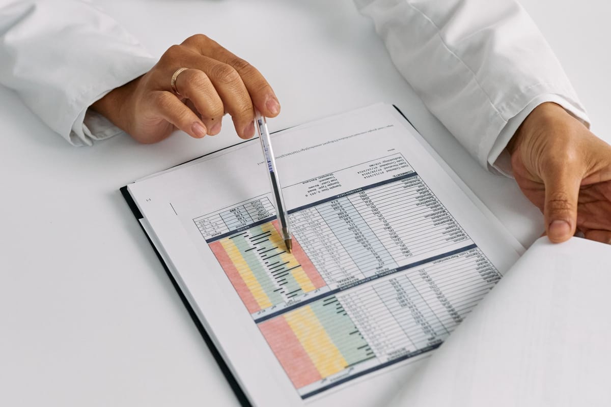 Doctor pointing a pen at a color-coded lab report on a clipboard