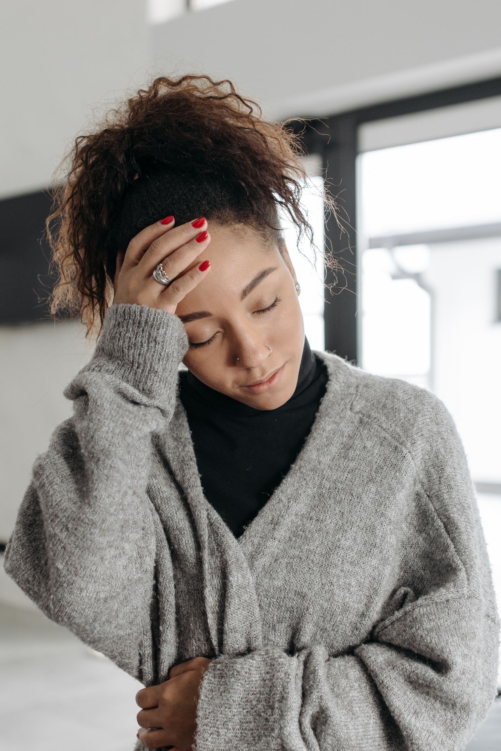 A woman resting a hand on her forehead - logging and exporting symptoms from Apple Health
